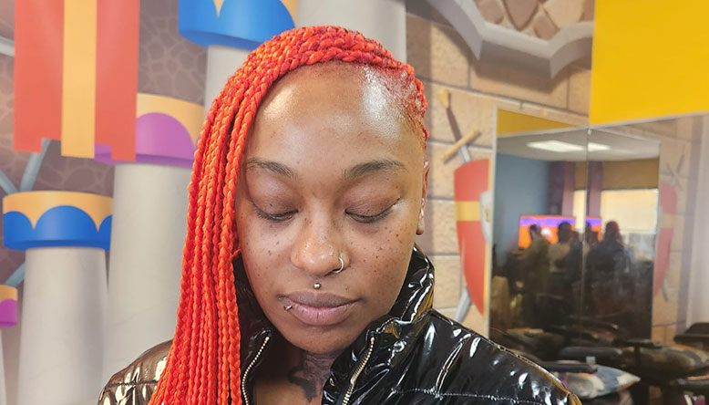 A woman with nose piercing and orange braiding